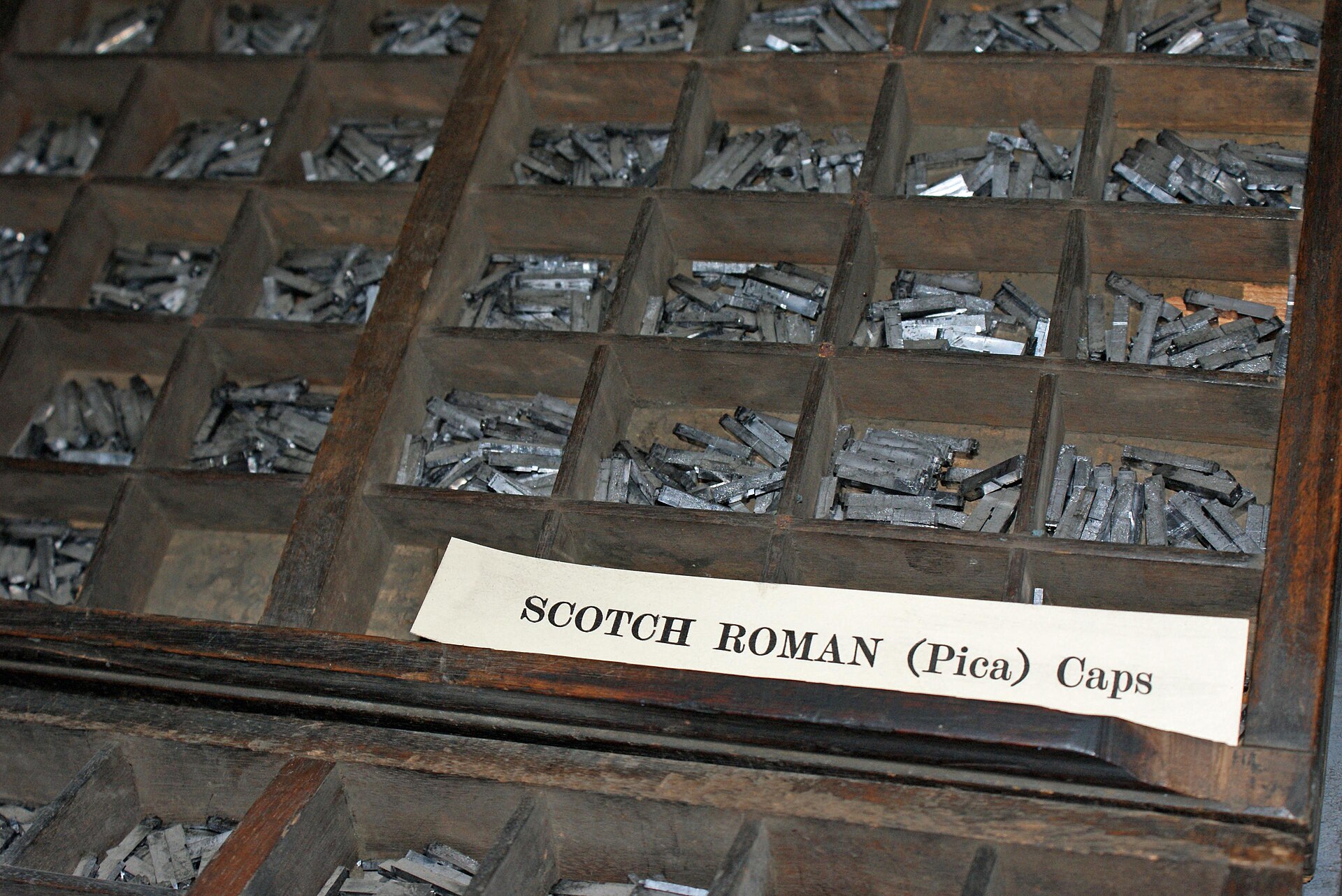 Metal printing type sorted into the wooden compartments of a type case.