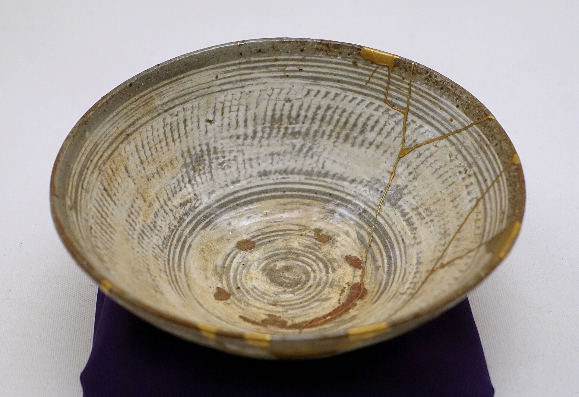 A sixteenth-century Korean tea bowl whose cracks have been repaired with seams of gold lacquer that stay plainly visible.
