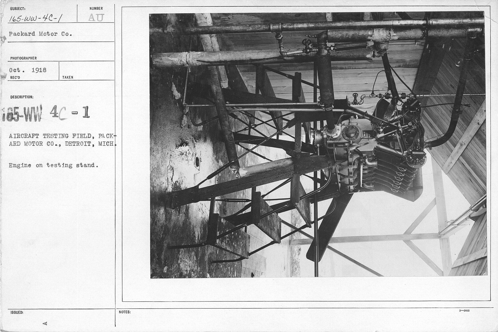 An aircraft engine mounted outdoors on a heavy test stand while several workers inspect the machinery.